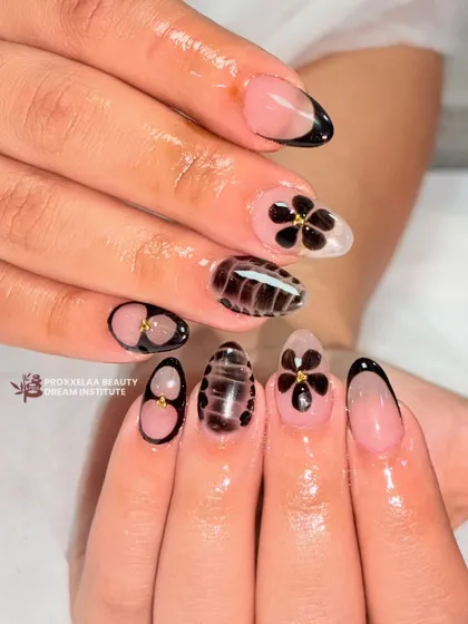 A chic and sophisticated design featuring a mix of styles. I combined a modern black French tip, hand-painted black flowers with gold centers, and a unique textured pattern.
