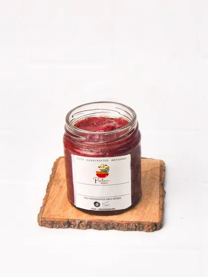 A jar of handmade strawberry jam, presented simply on a wooden slice against a white background. This allows the product's natural color and texture to shine.