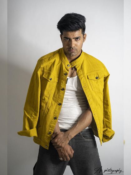 A confident and direct studio portrait. The simple styling with a white tank and yellow jacket creates a clean, modern look that is very versatile.