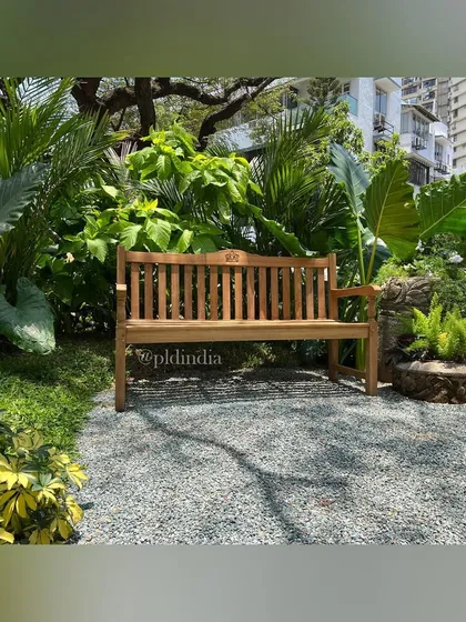 A simple wooden bench is placed on a gravel clearing, surrounded by a riot of tropical plants. This creates an inviting spot to sit and be completely immersed in the garden.