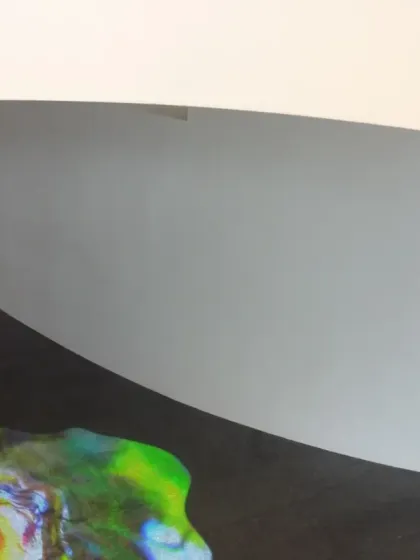 A close-up detail of the 'Amorphous Color Rain' projection at the Novartis Campus. The abstract, colorful forms flow across the floor, creating a liquid-like image that contrasts with the solid granite.