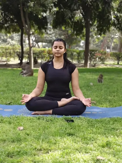 A student practices meditation in a park, demonstrating that the tools of yoga can be used anywhere to find tranquility. This practice of quieting the mind is especially beneficial for respiratory health and overall well being.