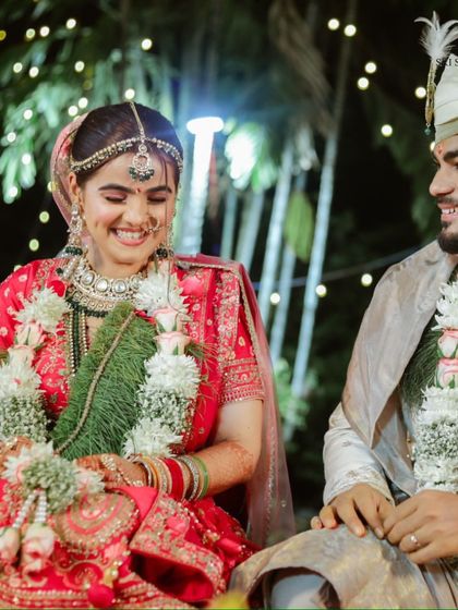 A happy moment between the bride and groom. Our bride is glowing in a red lehenga, accessorized with a layered Kundan and pearl jewellery set that adds to her wedding day radiance.