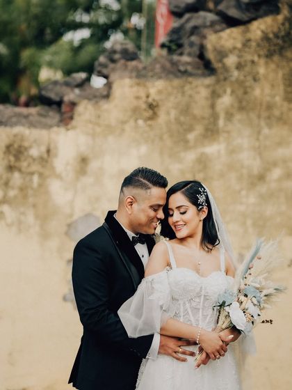 A warm, romantic portrait of the couple against a rustic, sunlit wall. This shot highlights their connection and the beautiful textures of the location.