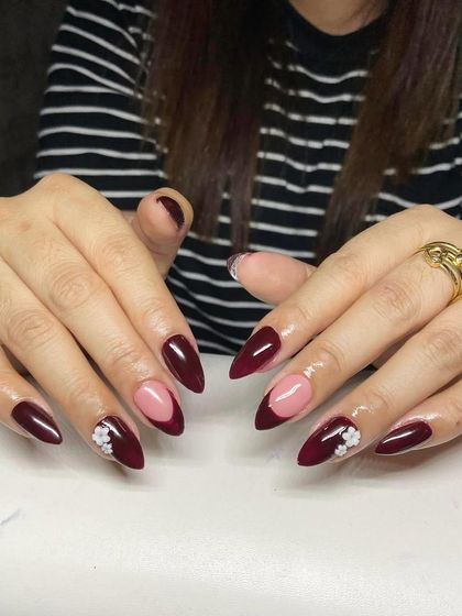 A duplicate of image 11, showing a deep maroon French manicure with 3D flower accents.