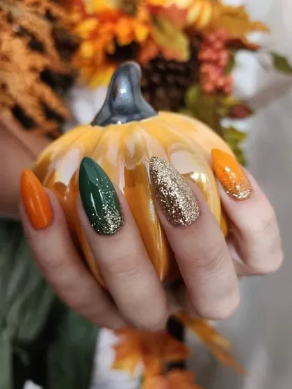 Perfect autumn nails. This set features fall colors like orange and deep green, with sparkling gold and green glitter accents.