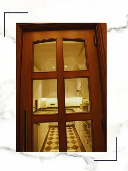 A beautiful glass-paneled wooden door that allows light to flow between the kitchen and the hallway while still providing a sense of separation. The design is both practical and elegant.