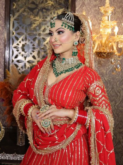 A smiling portrait of the bride, looking radiant in the complete red and green bridal ensemble.