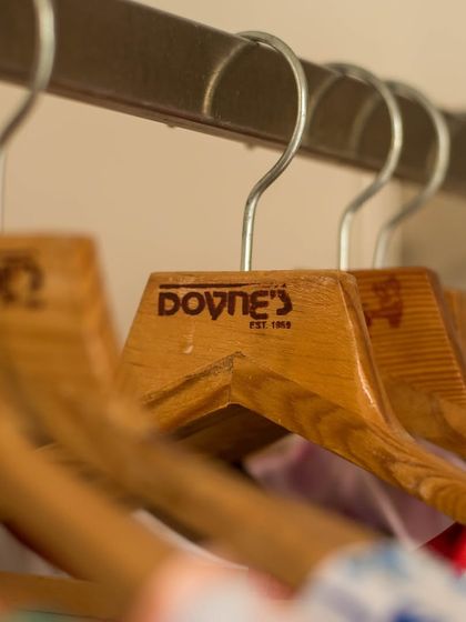 A shot of my custom wooden hangers, each bearing the Doyne's logo. It's a small detail that reflects my commitment to quality and brand identity.