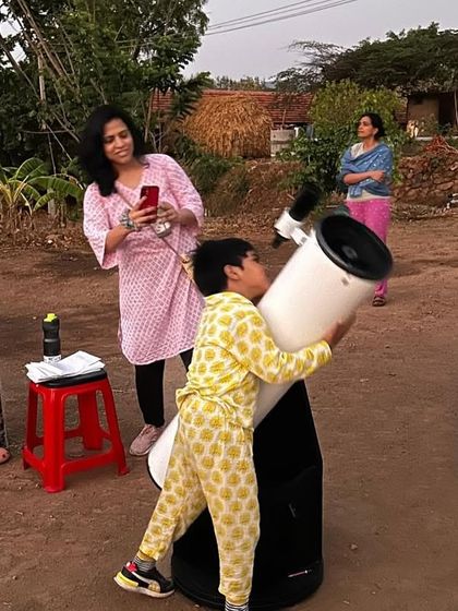 A child and adults share a telescope during our sky-gazing event. This photo beautifully illustrates multi-generational learning and the shared curiosity that connects us all. It's a perfect example of cosmic education in action.