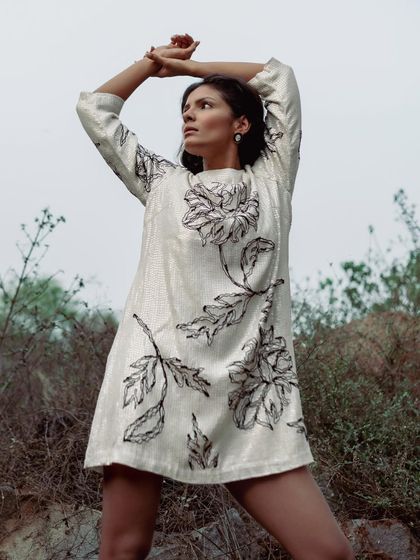 A creative shoot featuring a sequined floral dress. The model's pose and the outdoor setting give this shot a sense of freedom and movement, highlighting the texture of the dress in a dynamic way.