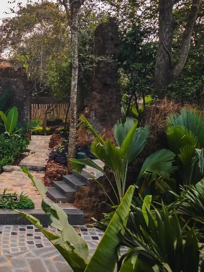 A stone pathway winds through the ruins and dense foliage at Sanctuary Bar. The landscape design creates a sense of adventure and discovery as guests explore the different zones of the restaurant.