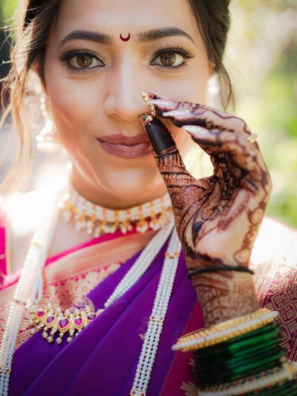 A close-up of a Maharashtrian bride in a vibrant purple nauvari saree. The focus is on her expressive eyes and the traditional nath, capturing the essence of Marathi bridal beauty.