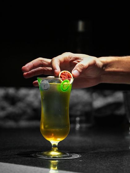 Service beyond expectation, where every detail shines. A bartender carefully places the final garnish on a cocktail, ensuring it is perfect before it reaches the guest.