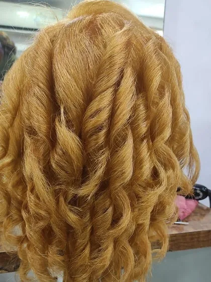 A student's work creating beautiful, bouncy curls on a mannequin. This shows a great understanding of heat styling and sectioning.