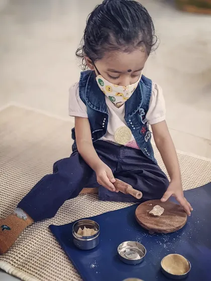 Practical life activities are the heart of our curriculum. Here, a child is using a small rolling pin and board to work with dough. These are not toys, but real, child-sized tools that help develop coordination, concentration, and a wonderful sense of accomplishment.