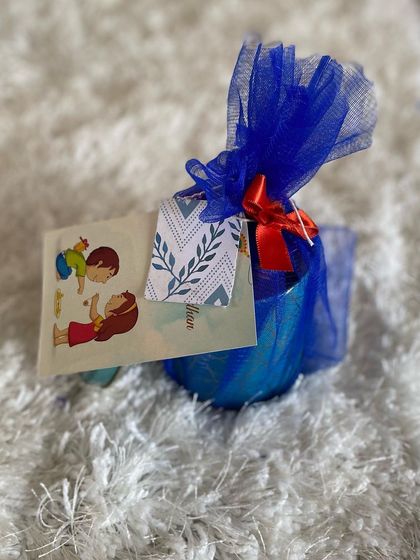 A beautifully wrapped Rakhi gift. This present is enclosed in blue tulle with a red ribbon and features a traditional Raksha Bandhan greeting card, ready to be delivered to a beloved brother.
