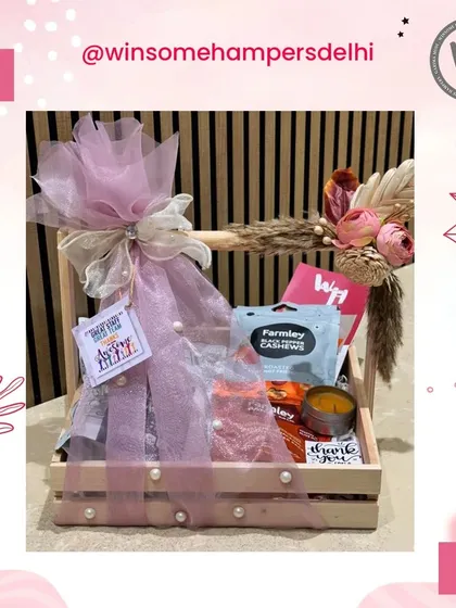 Personalized just for you. This custom hamper in a wooden crate is adorned with a large pink bow and filled with handpicked goodies.