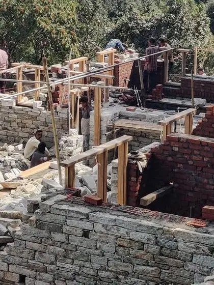 An aerial view of the guesthouse site during the early stages of construction. The layout of the separate structures is visible, scattered across the terrain to create a small, village-like cluster.