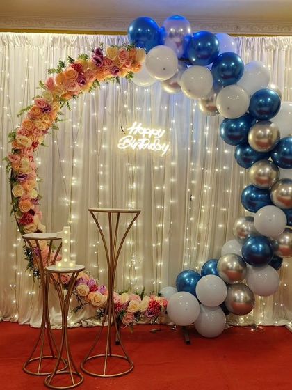 A unique half-floral, half-balloon circular arch against a fairy light curtain.
