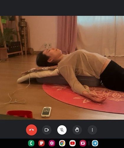 Even in an online session, we can achieve deep relaxation. Here, a student practices a supported restorative pose at home, allowing her nervous system to unwind and her body to release tension.