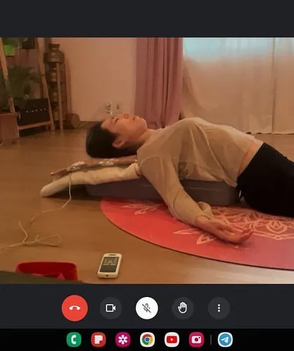 Guiding a student through a supported restorative pose during an online consultation. Using props like bolsters is crucial for relaxation, and I can instruct on how to use them effectively even through a screen.