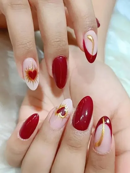 A perfect example of our detailed nail art on a classic red manicure. This look combines solid color, negative space, and delicate heart and line work for a modern romantic feel.
