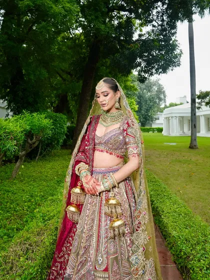 Our bride embodies grace in this full-length shot, showcasing her magnificent multi-toned lehenga. The makeup is designed to complement the grandeur of the outfit, with a regal finish that glows.