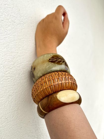 A detail shot of the lighter, more natural-toned bangle stack. The leaf motif and rattan texture give off a very bohemian, free-spirited vibe.