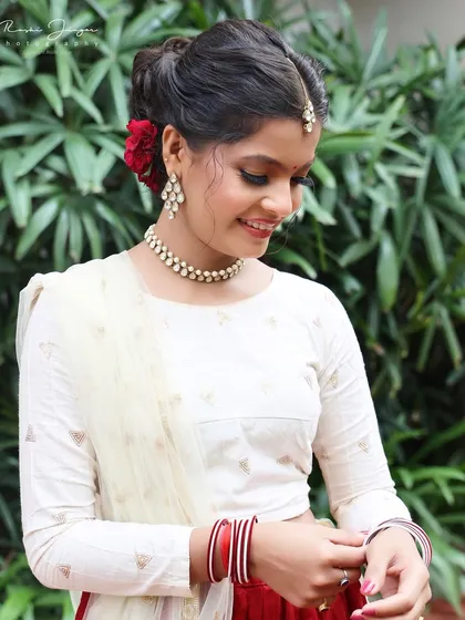 A candid moment showing the elegant hairstyle with a red rose and the soft, glowing makeup.