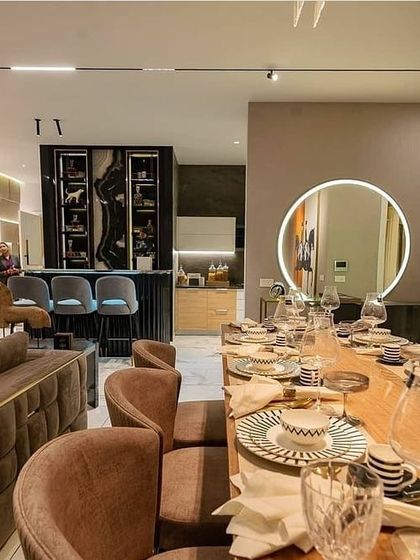 The dining area is defined by light. A large, circular backlit mirror on the wall adds a soft, diffused glow and acts as a piece of art, creating an intimate setting for meals while visually expanding the space.