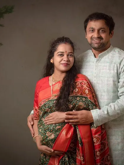 A classic couple's portrait with the mom-to-be in a traditional saree. The soft, painted backdrop adds a touch of fine art elegance.