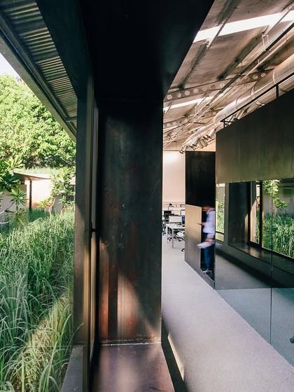 A courtyard filled with lemon grass and champa trees is nestled within the ATE adaptive-reuse project in Pune. This sensory garden offers a fragrant, natural retreat for employees, visible from the surrounding workspaces.