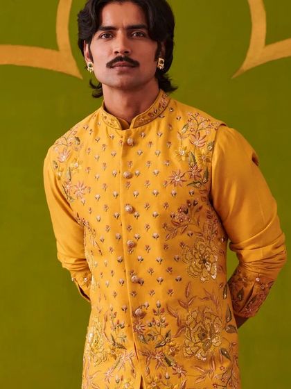 A close-up of the vibrant yellow embroidered waistcoat. The detailed floral embroidery and the rich color make it a perfect choice for a Haldi or Sangeet ceremony.