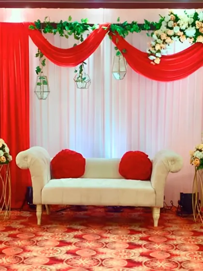 A full view of the red and white themed stage, showcasing the balance between the bold red drapes and the soft white floral arrangements.