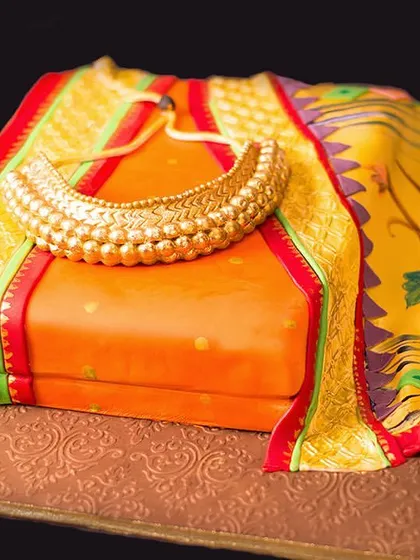 An orange Paithani saree cake, created for Navratri, complete with an edible golden necklace.