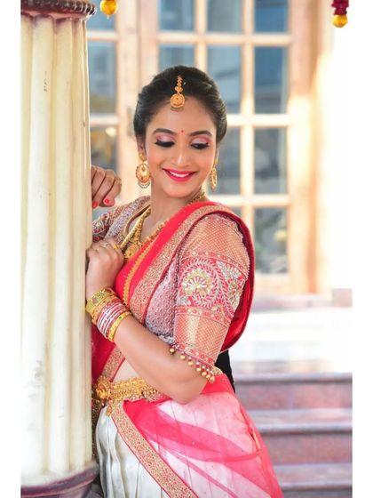 A smiling client in her custom Yukba half-saree lehenga. The detailed embroidery on the blouse sleeves adds a touch of sparkle to her traditional attire.