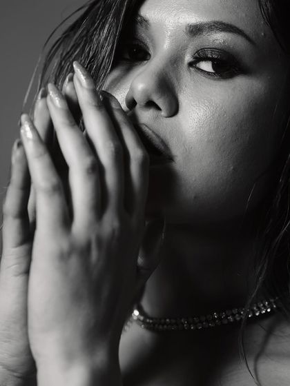 A soft and mysterious portrait. The model's hands frame her face, creating a sense of intimacy, while the black and white tones and soft focus add a timeless, film-noir feel.