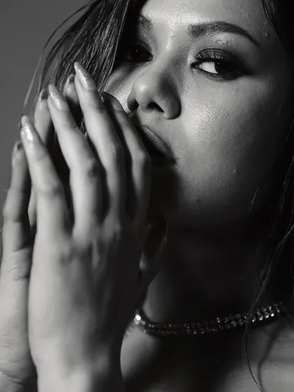 Another artistic black and white portrait, this time with the model's hands framing her face. The soft focus and deep shadows add a layer of mystery and vulnerability to the shot.