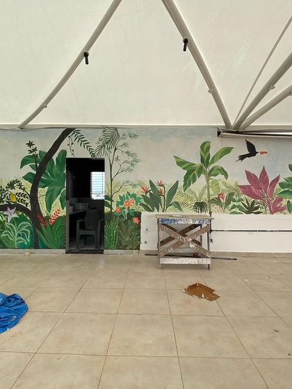 We call this our tropical paradise. We transformed the walls of a restaurant with a misty forest theme, covering even the doors to create a seamless, immersive jungle experience with colorful birds and lush greenery.