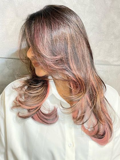 This image showcases a beautiful blend of brown hair with soft pink highlights. It's a playful and trendy way to add a pop of color.