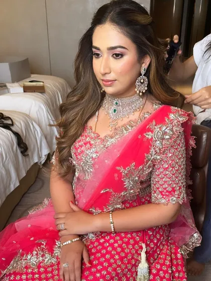 A candid moment during hair styling. The makeup is already flawless, providing a perfect base for the final look.