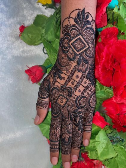 The dark, fresh henna paste looks so striking against the skin and the vibrant red flowers.