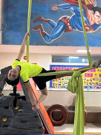 With Superman flying in the background, this young aerialist strikes a powerful pose, showing off her own superhero strength and flexibility.
