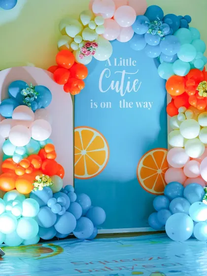 A "Little Cutie is on the way" citrus-themed baby shower. The vibrant blue and orange balloon arrangement and orange slice graphics create a fresh and unique party theme.