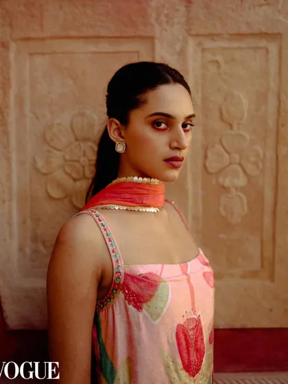A striking portrait for Ruhr India, selected for PhotoVogue. The model's direct gaze and the vibrant colors of her outfit stand out against a carved stone wall.