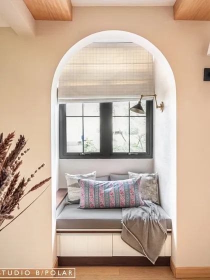 An arched niche with a built-in window seat creates a perfect, cozy reading nook. This architectural detail adds charm and functionality, making the most of the available space.