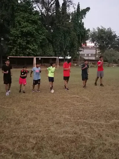 A coach addressing a group of young athletes on the field, explaining the next set of drills and setting expectations for the session.