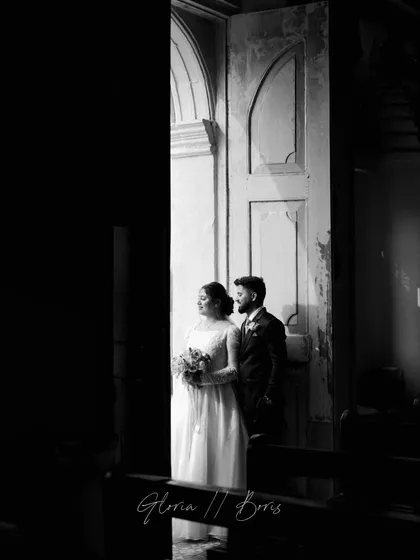 A dramatic black and white shot of the couple standing in a doorway inside the church, using natural light to create a powerful, artistic portrait.