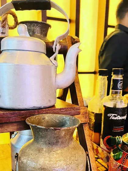 A rustic chai station set up for a baby shower, featuring a classic aluminum kettle and milk can.